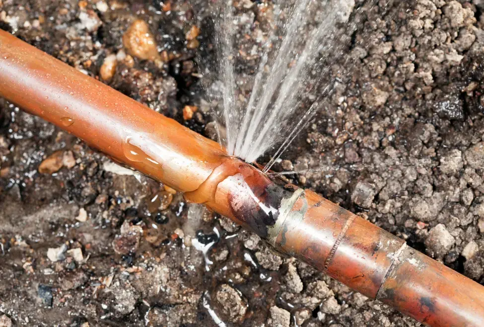 Close-up of a burst copper pipe spraying water, a plumbing emergency