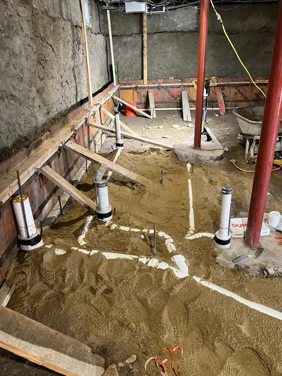 Plumbing rough-in piping being installed in a home foundation during construction
