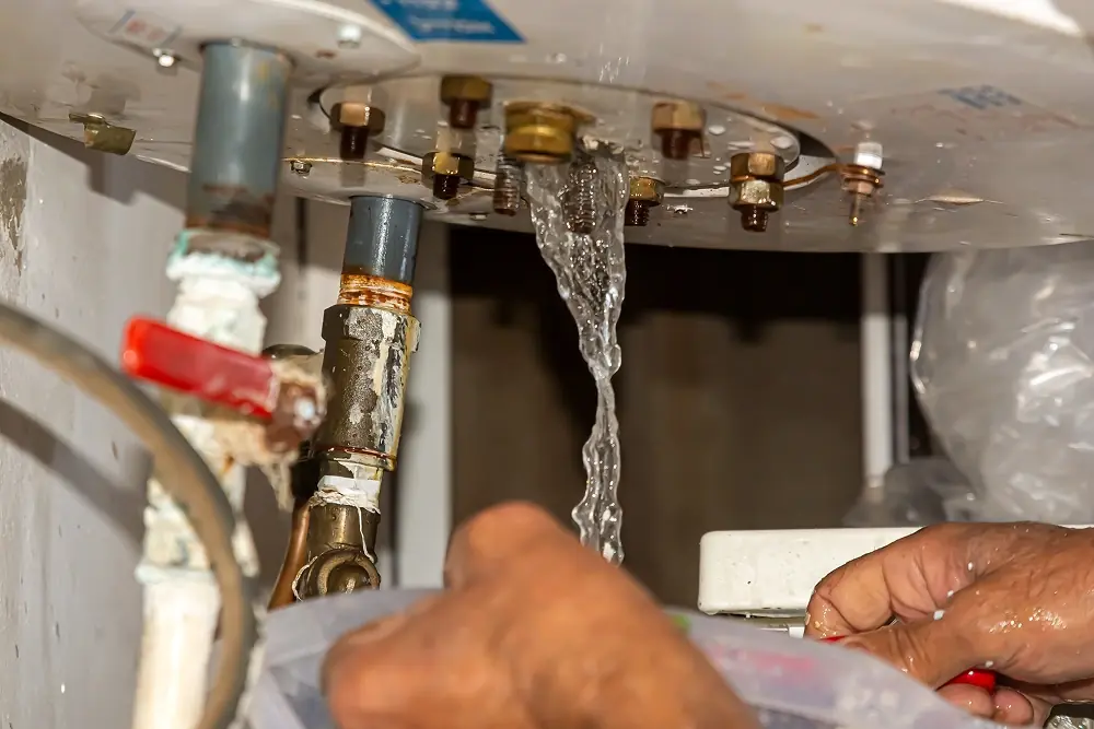 Technician repairing a leaking water heater during an emergency service call